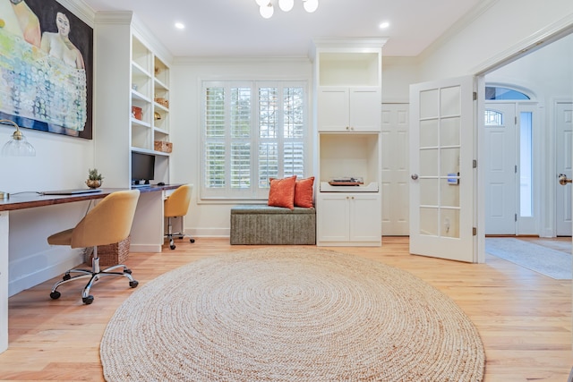 office with ornamental molding, built in desk, and light hardwood / wood-style flooring