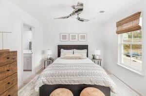 bedroom with connected bathroom, multiple windows, and ceiling fan