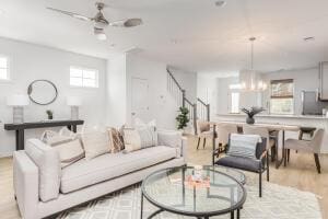 living room featuring light hardwood / wood-style floors and ceiling fan with notable chandelier