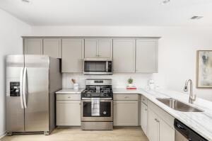 kitchen featuring appliances with stainless steel finishes, gray cabinetry, and sink