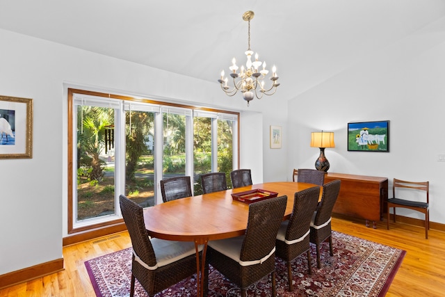 dining room featuring a notable chandelier, vaulted ceiling, and light hardwood / wood-style flooring