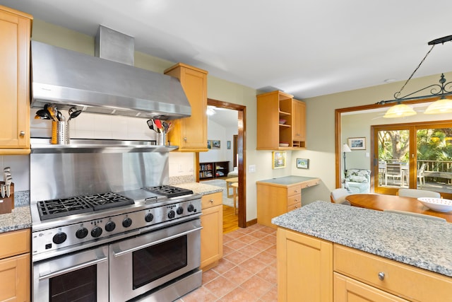 kitchen with light stone counters, range hood, double oven range, decorative light fixtures, and light brown cabinetry