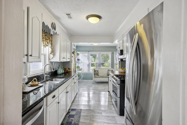 647 Ellis St, Mount Pleasant, SC 29464 - kitchen with appliances with stainless steel finishes, a sink, white cabinetry, a textured ceiling, and dark stone countertops