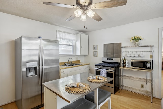 647 Ellis St, Mount Pleasant, SC 29464 - kitchen featuring stainless steel appliances, a sink, white cabinets, light wood-style flooring, and light countertops