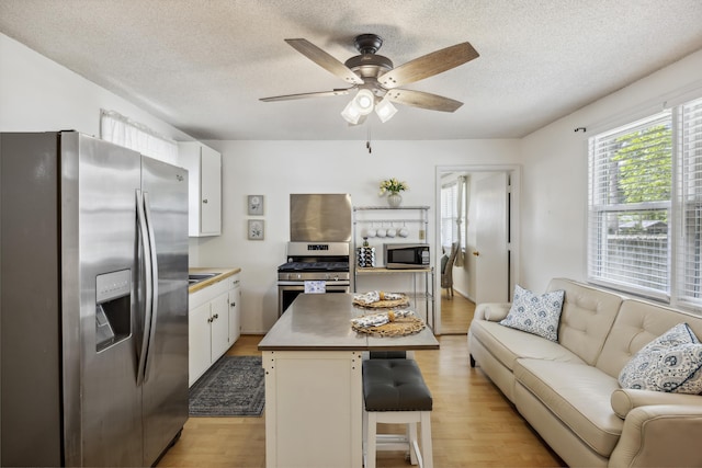 647 Ellis St, Mount Pleasant, SC 29464 - kitchen with stainless steel appliances, open floor plan, light wood-style flooring, a textured ceiling, and a breakfast bar