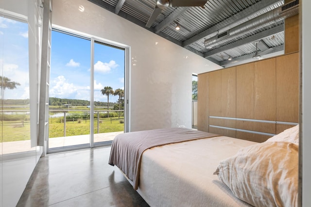 bedroom featuring concrete flooring, a water view, and access to exterior