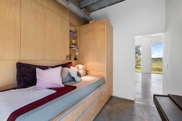 bedroom featuring a high ceiling, access to outside, and wooden walls