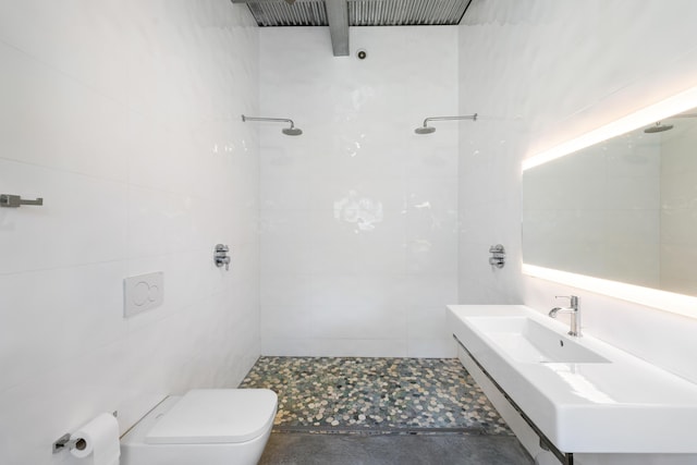 bathroom featuring sink, toilet, a tile shower, and tile walls