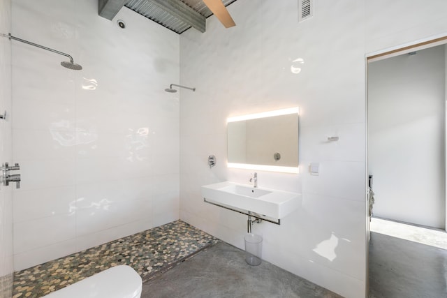 bathroom with concrete floors, sink, tiled shower, and toilet