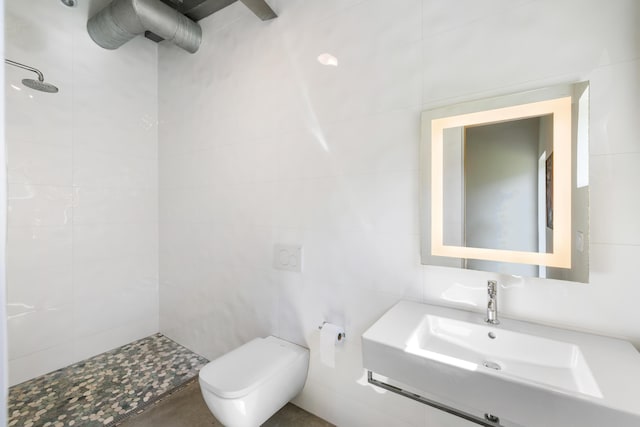 bathroom featuring toilet, tile walls, sink, and tiled shower