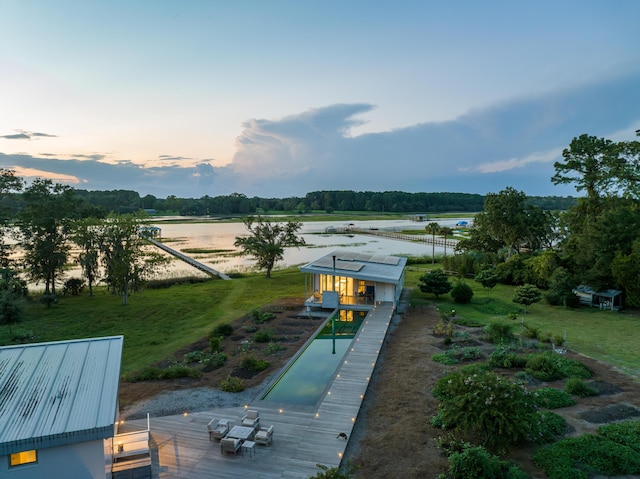 surrounding community with a water view and a lawn