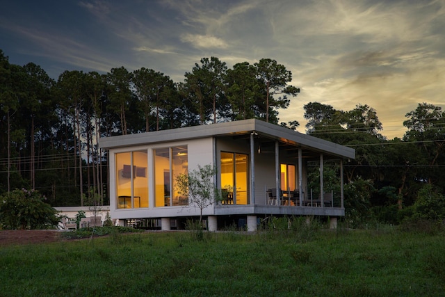 back house at dusk featuring a lawn