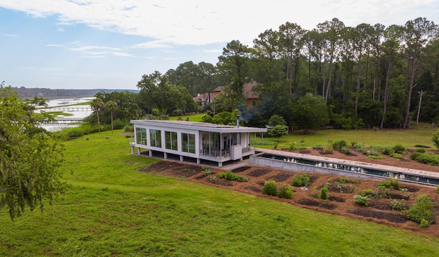 rear view of house with a water view and a lawn