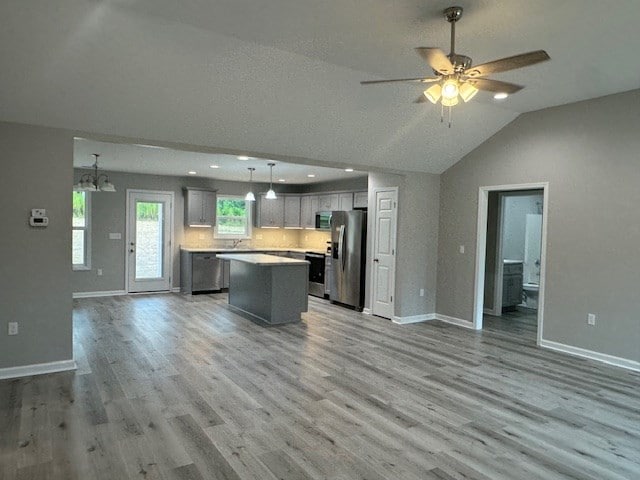 kitchen with light hardwood / wood-style flooring, hanging light fixtures, appliances with stainless steel finishes, and a kitchen island