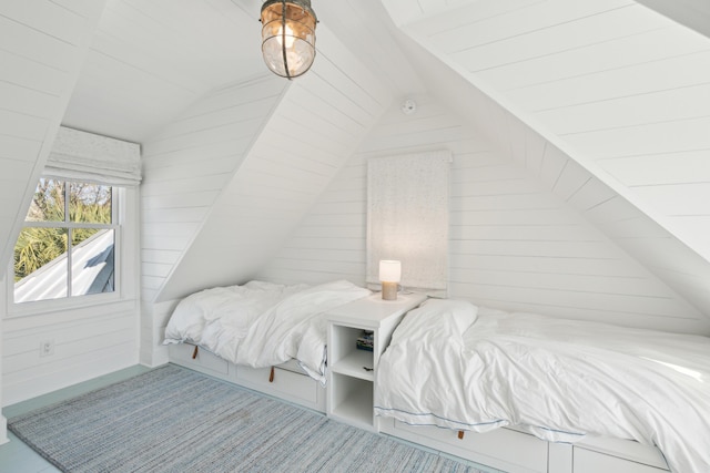 bedroom featuring lofted ceiling and wooden walls