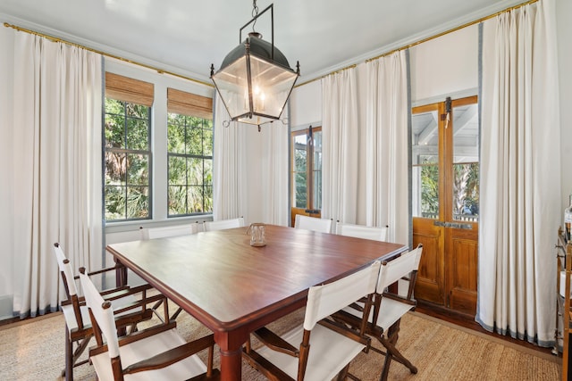 dining space with light hardwood / wood-style floors, ornamental molding, and an inviting chandelier