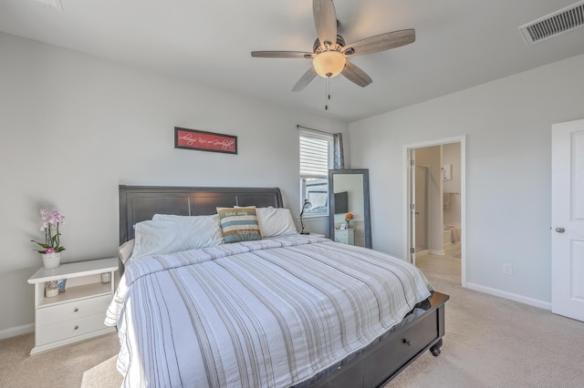 bedroom featuring baseboards, visible vents, ensuite bathroom, and light colored carpet