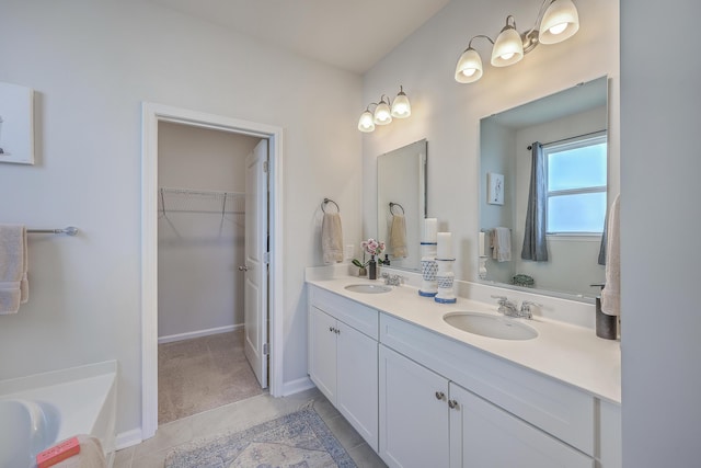 bathroom featuring double vanity, tile patterned flooring, a sink, and a walk in closet