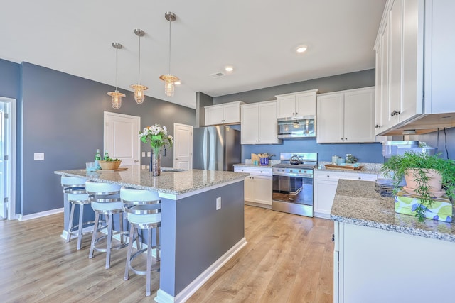 kitchen with appliances with stainless steel finishes, visible vents, white cabinetry, and light wood-style flooring