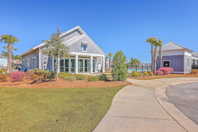 view of front of house featuring a front lawn, board and batten siding, and fence