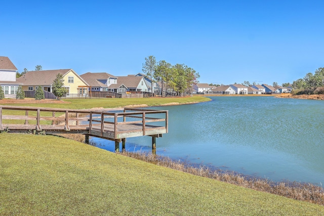 view of dock with a lawn, a water view, and a residential view