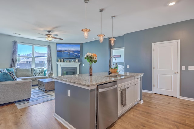 kitchen featuring dishwasher, a glass covered fireplace, light wood-style flooring, pendant lighting, and a sink