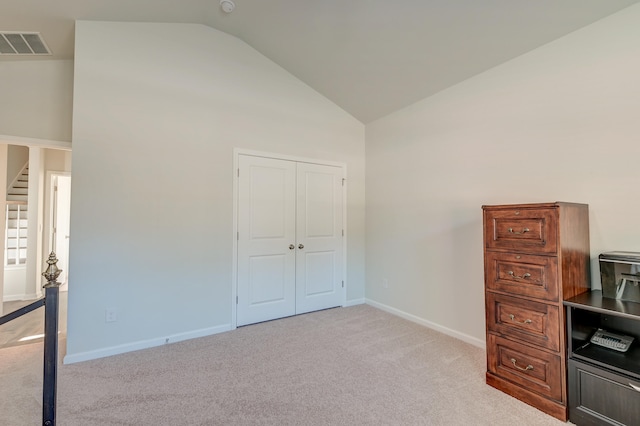 unfurnished bedroom featuring light carpet, high vaulted ceiling, and a closet