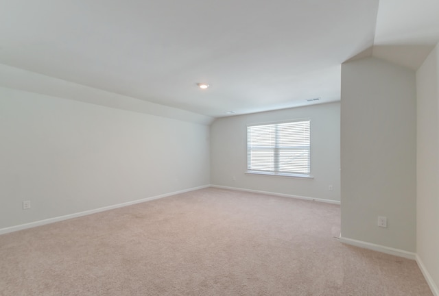 empty room featuring light carpet and vaulted ceiling