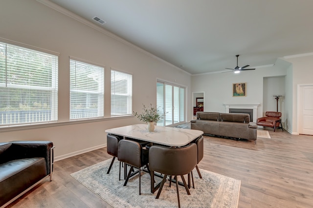 dining space featuring ceiling fan, light wood-type flooring, and crown molding