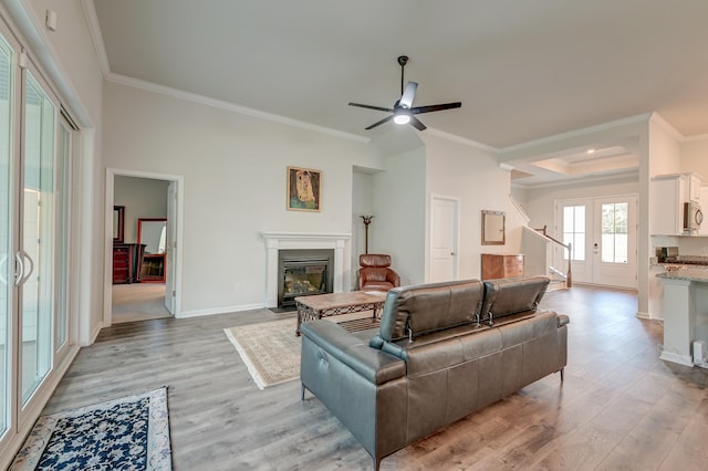 living room with light wood-type flooring, ceiling fan, and crown molding