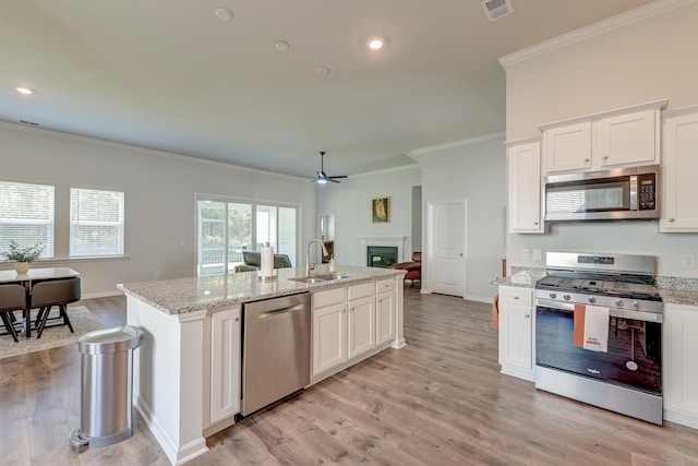 kitchen with appliances with stainless steel finishes, light hardwood / wood-style floors, a kitchen island with sink, and sink