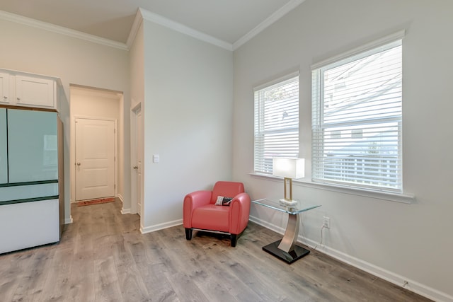 sitting room with ornamental molding and light wood-type flooring