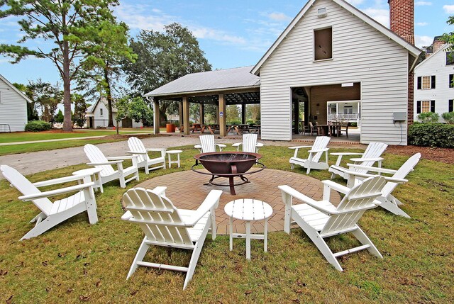 back of house featuring a lawn, a patio, and an outdoor fire pit