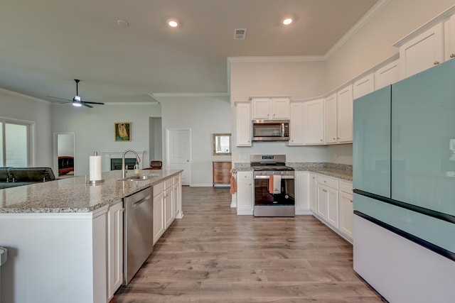 kitchen with sink, white cabinets, light wood-type flooring, and appliances with stainless steel finishes