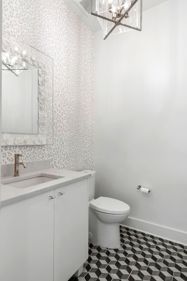 bathroom featuring a notable chandelier, vanity, and toilet