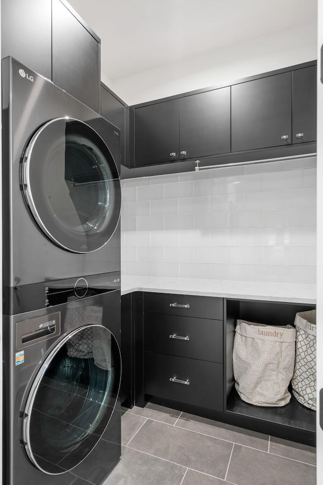 laundry room featuring cabinets, light tile patterned floors, and stacked washer / drying machine