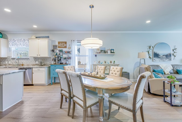 dining space with crown molding, a healthy amount of sunlight, sink, and light hardwood / wood-style floors