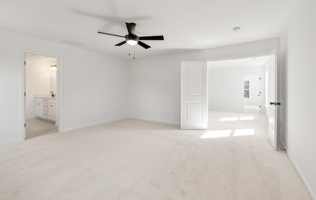 unfurnished bedroom featuring ceiling fan, light carpet, and ensuite bath