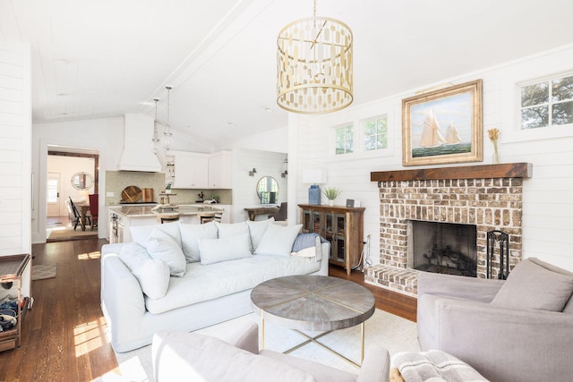 living room featuring lofted ceiling, a chandelier, dark hardwood / wood-style flooring, and a brick fireplace