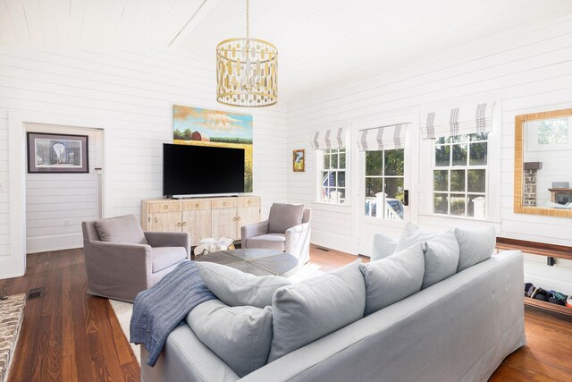 living room with an inviting chandelier, lofted ceiling, and dark hardwood / wood-style flooring