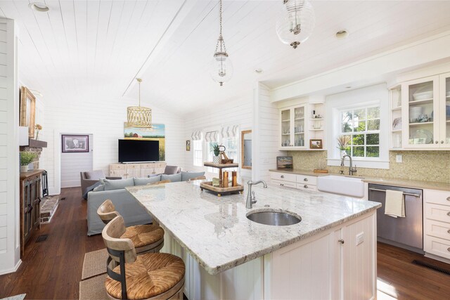 kitchen with decorative light fixtures, dark hardwood / wood-style floors, a center island with sink, stainless steel dishwasher, and sink