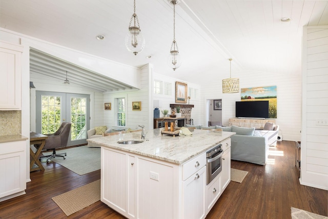 kitchen featuring pendant lighting, lofted ceiling with beams, white cabinetry, sink, and oven