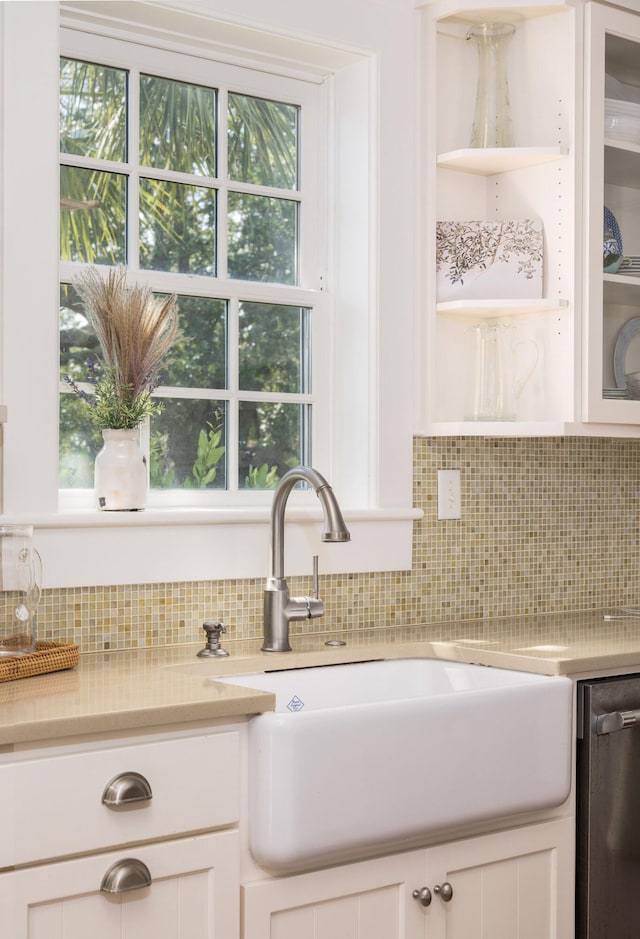 kitchen with stainless steel dishwasher, sink, tasteful backsplash, and white cabinetry