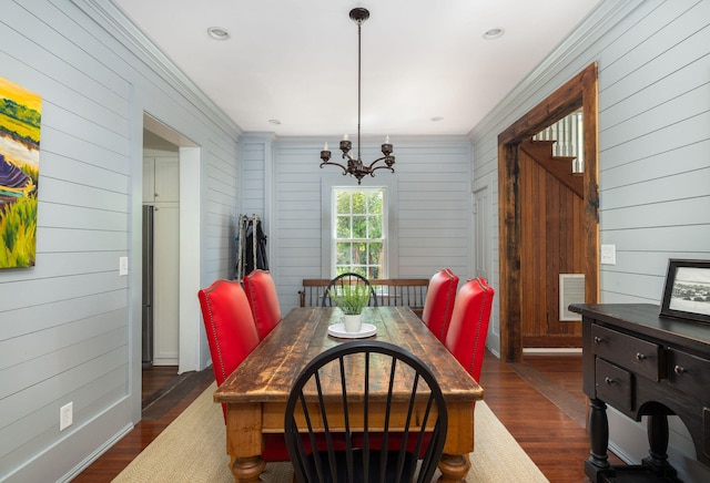 dining room featuring a notable chandelier, dark wood-type flooring, and wooden walls