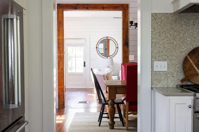 interior space with hardwood / wood-style floors, white cabinetry, high end refrigerator, and backsplash