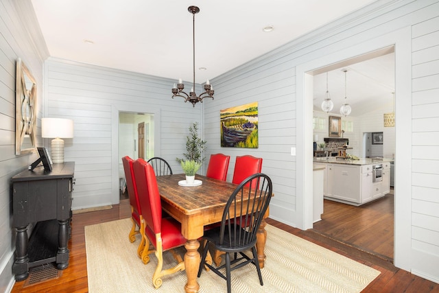 dining space featuring crown molding, dark hardwood / wood-style flooring, and a notable chandelier