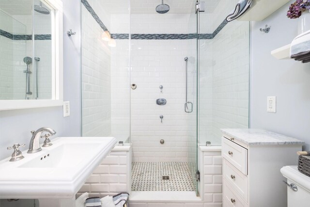 bathroom featuring sink, an enclosed shower, and toilet