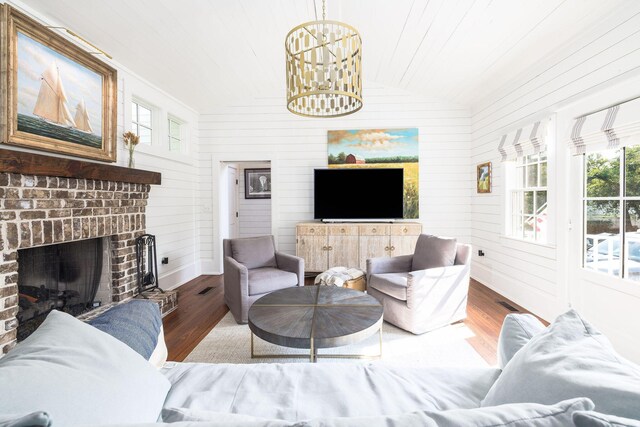 living room featuring a brick fireplace, hardwood / wood-style floors, wood walls, and vaulted ceiling