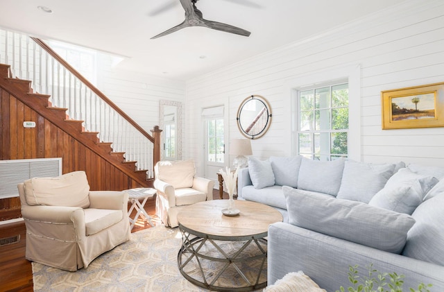 living room with hardwood / wood-style flooring, plenty of natural light, ceiling fan, and wood walls