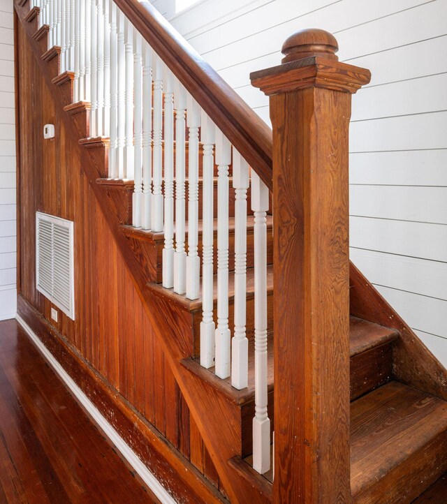 stairs with wooden walls and dark wood-type flooring